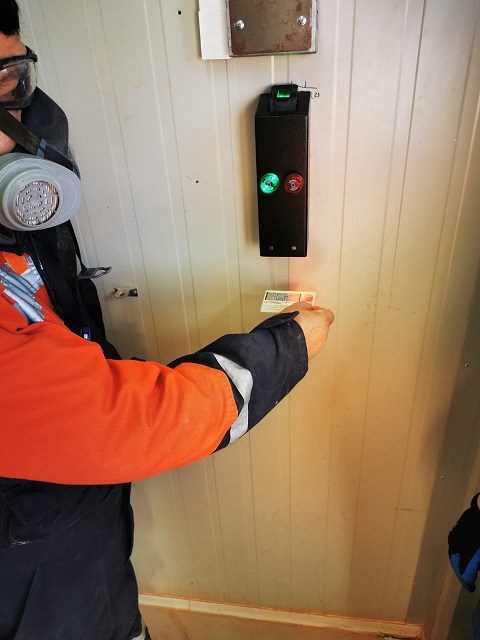 Trabajador validando su credencial en un control de acceso para puerta industrial